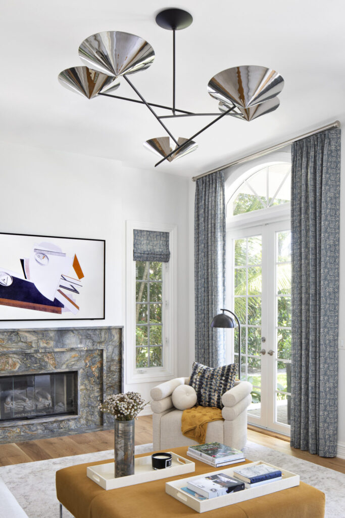 Close-up of dramatic marble fireplace with metallic chandelier in a Palm Beach living room.