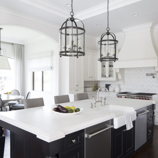 Bright Palm Beach kitchen with white cabinetry, oversized island, black lantern pendant lights, and farmhouse sink designed by Krista + Home.