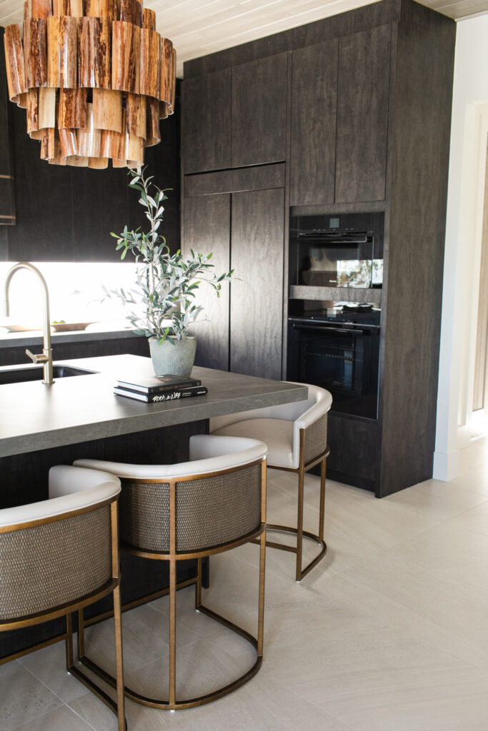 Statement kitchen with MadeGoods organic pendants, black cabinetry, and Palecek barstools in a Modern Balinese North Palm Beach home.