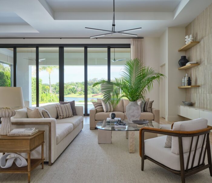 Palm Beach living room with neutral furnishings, soft textures, and lush greenery framing a serene golf course view.