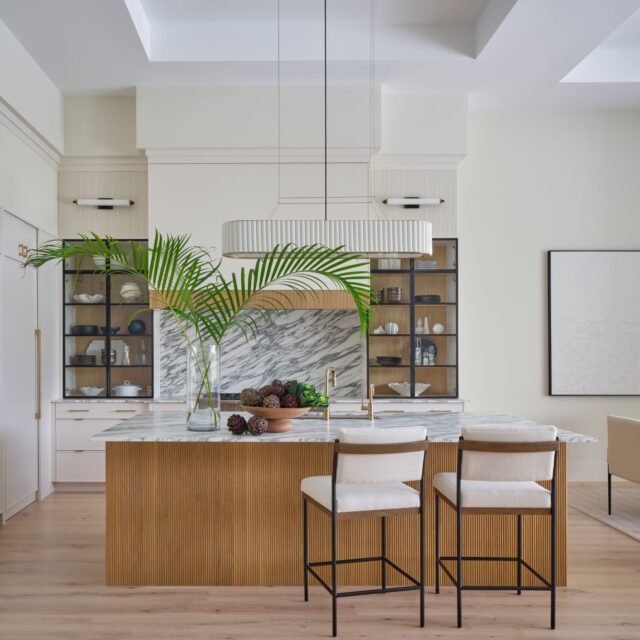 Modern Palm Beach kitchen with marble backsplash, gold fixtures, and vibrant greenery adding a pop of color.