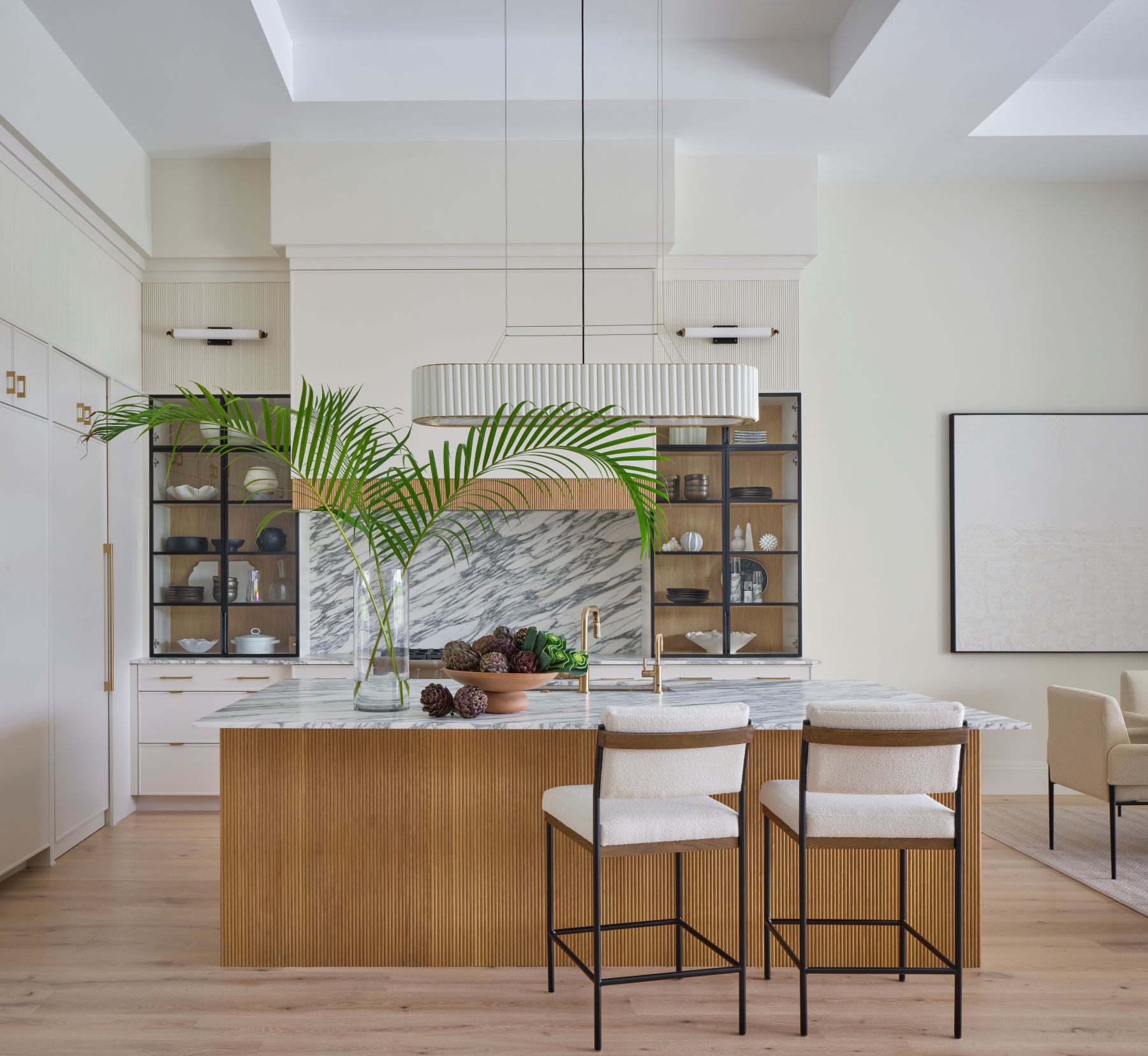 Modern Palm Beach kitchen with marble backsplash, gold fixtures, and vibrant greenery adding a pop of color.