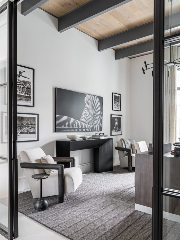 Cozy reading nook with blush-painted built-in bookshelves, brass hardware, a white desk with gold legs, floral curtains, and a woven basket beneath the window.